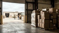 Warehouse interior with stacked cardboard boxes and open loading dock doors, logistics and shipping storage facility.