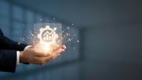 Young male professional in business attire holding glowing holographic house icon with digital particles, representing real estate investment, property management, and smart home technology solutions.