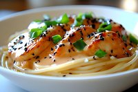 Grilled shrimp with black sesame seeds served on spaghetti pasta garnished with fresh herbs in white bowl, close up view of Asian fusion cuisine.