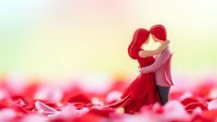 Romantic couple embracing in field of red rose petals with soft dreamy lighting for wedding and love concepts.