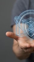 Businessman hand holding holographic shield icon representing cybersecurity, data protection and digital security technology concept for business applications.