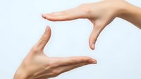 Two hands forming protective frame gesture on white background for business presentation and safety concept.