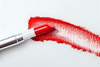 Vibrant red lipstick smear with makeup brush on white background, showcasing rich pigment texture for cosmetic product photography.