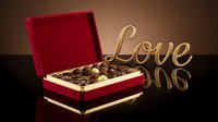 Luxury red velvet box filled with assorted chocolates beside a golden Love sign, perfect for Valentine's Day and romantic gifting concepts.