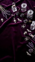 Gothic witchcraft altar with glass bottles, skulls, spiders, bats and lavender on purple velvet fabric for Halloween decoration and mystical ritual setup.