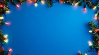 Festive border with glowing multicolored Christmas lights and pine branches framing bright blue background, creating magical holiday atmosphere for seasonal designs.