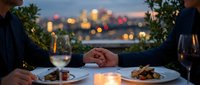Romantic dinner date with couple holding hands at elegant restaurant terrace overlooking city lights at twilight with wine and gourmet meals.