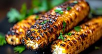 Grilled corn on cob with charred grill marks and fresh herbs garnish on dark background, close up view showing caramelized kernels and smoky texture.