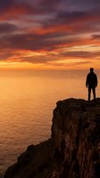 Silhouetted figure standing on rocky cliff overlooking golden sunset ocean horizon with dramatic fiery sky, conveying contemplation and adventure for travel and lifestyle concepts.