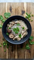 Asian noodle soup with shiitake mushrooms and fresh herbs in black bowl on rustic wooden cutting board for healthy cooking and restaurant menu design.