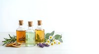 Natural essential oils in glass bottles with cork stoppers, herbs and flowers for aromatherapy, spa treatments and wellness products on white background.