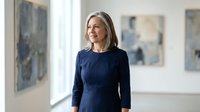 Confident mature Caucasian businesswoman in navy dress smiling in modern office gallery space with abstract artwork on walls for corporate success.