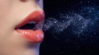 Woman with glossy coral lips exhaling sparkling stardust against deep blue cosmic background with twinkling stars and nebula effects.