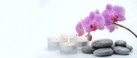 Spa wellness concept with purple orchid flowers, smooth gray stones and white candles on clean background for relaxation and meditation treatments.
