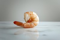 Fresh cooked shrimp on white marble surface with soft reflection, minimalist food photography composition in natural light with clean background.