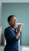 Happy African American businesswoman in glasses holding paper airplane in modern office setting for creative business concepts and startup ideas.