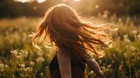 Young woman with flowing red hair dancing in golden sunlight meadow with wildflowers during sunset creating dreamy atmospheric moment for wellness lifestyle content.