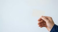 Male hand holding blank white card against neutral background, suitable for business messaging, advertising, and promotional campaigns.