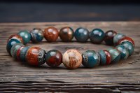 Handcrafted beaded bracelet with natural gemstones in earth tones on rustic wooden background for jewelry and accessories design projects.