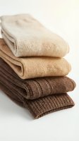Stack of folded knitted wool socks in neutral beige and brown tones arranged neatly on a white background for cozy fashion retail.