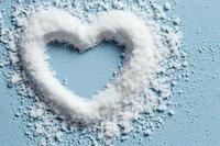 Heart shape made from white flour powder on light blue background for baking and cooking concepts.