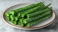 Fresh cut green asparagus spears arranged on white ceramic plate with rustic rim, close up view showing tender stalks and vibrant color against light background.
