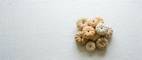 Small decorative pumpkins and gourds arranged on white wooden surface for autumn seasonal decor and harvest themed designs.