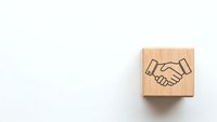 Wooden cube with handshake symbol on white background representing business partnership, teamwork and cooperation concepts for corporate design.