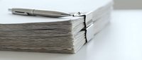Thick stack of papers with a silver pen on top, placed on a white surface, symbolizing documentation and office work.