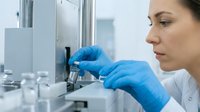 Female scientist in laboratory conducting chemical analysis with test tubes and equipment wearing protective gloves for research and development purposes.