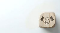 Wooden cube with handshake symbol on white background representing business partnership, teamwork and cooperation concepts for corporate design.