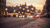 Romantic urban street scene with heart-shaped bokeh lights creating dreamy atmosphere during golden hour sunset for Valentine's Day celebrations.