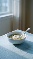 Oatmeal cereal bowl with fresh fruit and yogurt on white table by window with natural light for breakfast and healthy eating concepts.