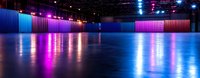 Empty modern event space with vibrant neon lighting reflecting on polished floor, featuring blue and pink illuminated walls creating dramatic atmosphere for concerts or shows.