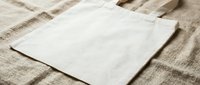 Natural cotton canvas tote bag mockup on linen fabric background for branding and design projects.