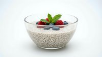 Chia seed pudding with fresh berries and mint in glass bowl on white background. Healthy breakfast dessert with raspberries and blueberries isolated.