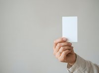 Hand holding blank white card against neutral background, suitable for business presentations, marketing campaigns, advertising mockups, and promotional materials.