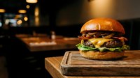Gourmet burger with melted cheese, lettuce, and caramelized bun on wooden board in restaurant setting, ideal for food service marketing and culinary content.