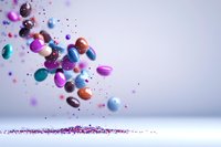 Colorful pills and capsules floating in air with glitter scattered below, captured in dynamic motion against soft gray background. Medical concept photography.