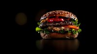 Juicy black burger with beef patty, fresh vegetables and sesame bun on dark background with dramatic lighting and reflective surface. Food photography.