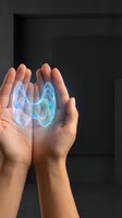 Cupped hands holding glowing blue energy orb with ethereal light effects against dark modern interior background for healing and wellness concepts.