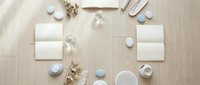 Minimalist spa wellness flat lay with white cosmetic bottles, natural soap bars, cotton pads and decorative stones on wooden background for skincare branding.
