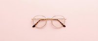 Pair of round eyeglasses with gold metal frame isolated on soft pink background, suitable for fashion, optical retail, and eyewear design projects.