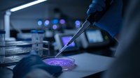 Scientist in blue gloves conducting laboratory research with pipette and petri dish under UV light in modern medical facility for scientific analysis.