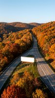 Scenic autumn highway winding through vibrant fall foliage with rolling hills and golden hour lighting creating stunning seasonal landscape for travel content.