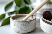 Minimalist ceramic bowl with speckled texture and bamboo utensil against blurred green foliage background, showcasing modern sustainable lifestyle and spa aesthetics.