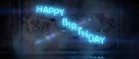 Cyan neon sign displaying Happy Birthday message glowing against dark brick wall with atmospheric lighting effects for celebrations and party events.