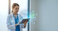Female doctor using digital tablet with holographic medical data interface in modern hospital setting for healthcare technology applications.