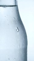 Chilled glass bottle with condensation droplets and water beads on surface, suitable for beverage, refreshment, and drink advertising campaigns.