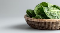 Fresh green cabbage leaves in woven basket on white background, suitable for food, cooking, nutrition, and healthy eating design projects.
